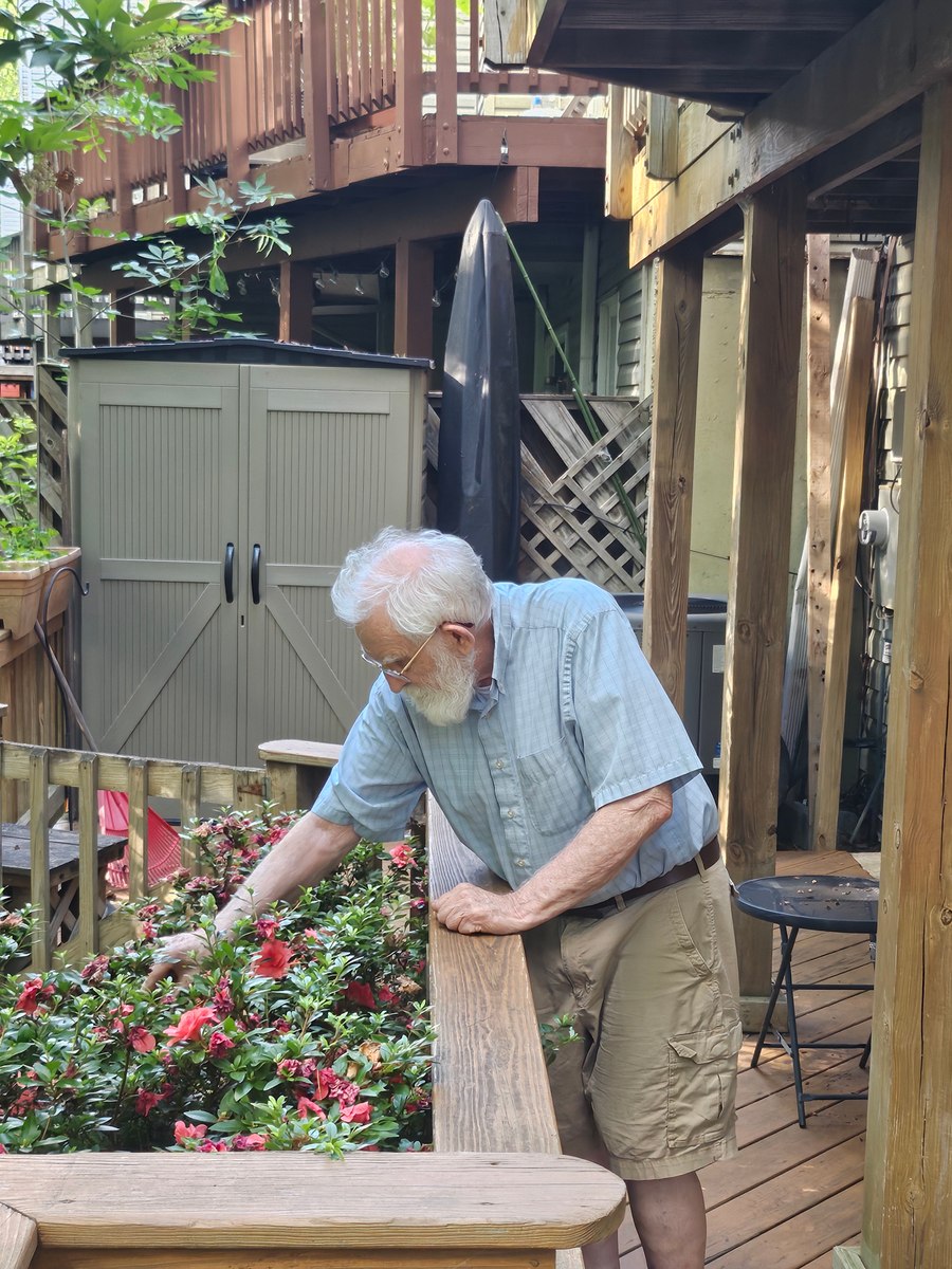 Grandfather reaching toward plants beside a wooden railing