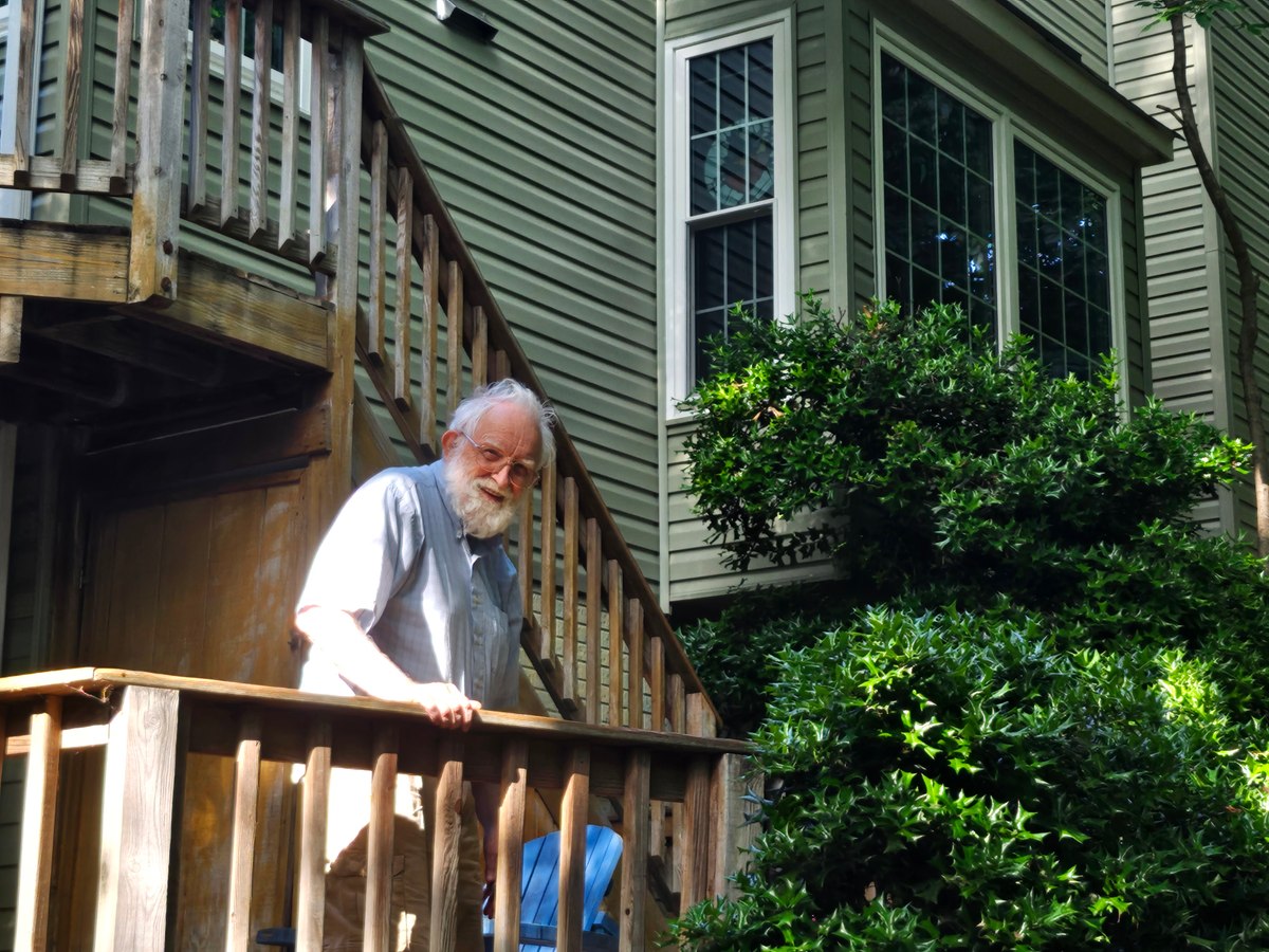 Grandfather leaning against a wooden fence beside a house